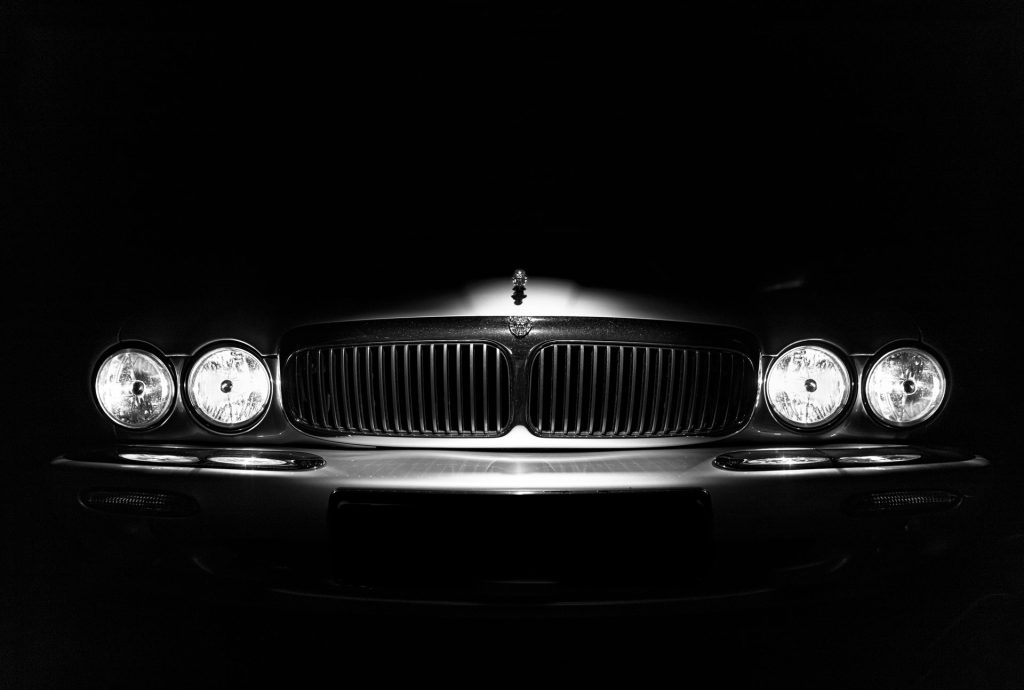 Photo de la calandre avant d'une Jaguar de collection. Image éclairée en lumière de cinéma style Harcourt.
